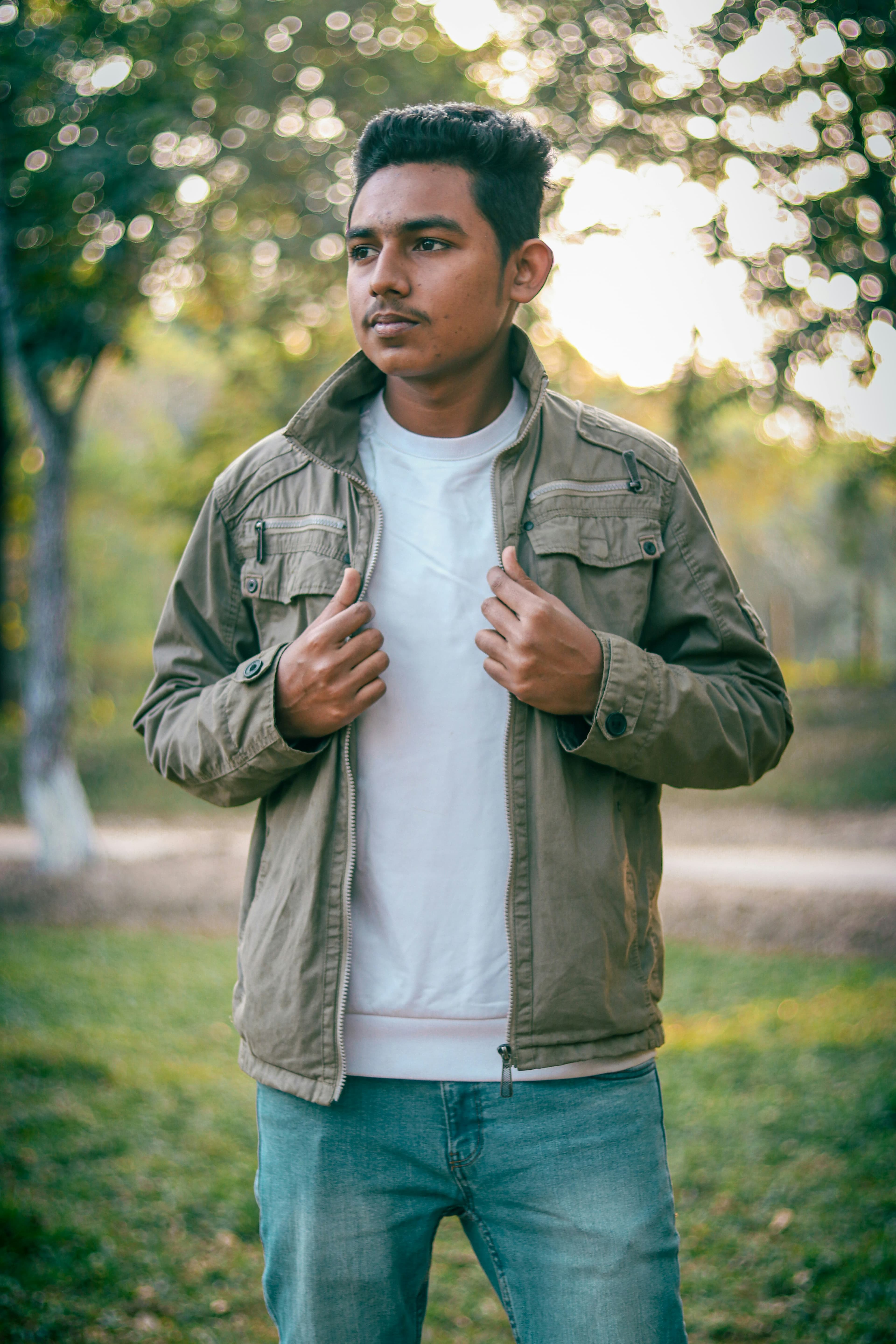 A young man in a white shirt posing against a wall.